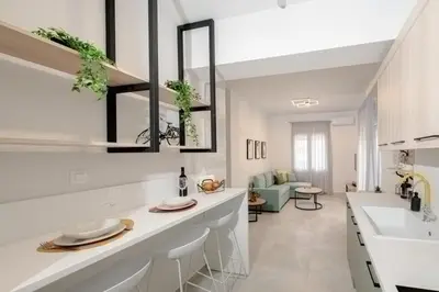 a white kitchen with a counter and a living room at Minimal Chic Retreat Suite in Chania Town