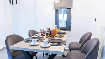 a dining room table and chairs with food on it at Seascape Luxury Apartment in Kounoupidhianá