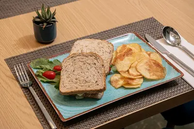 a sandwich and chips on a blue plate on a table at Miss Marrone City Hotel in Chania Town