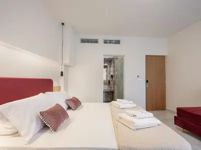a bedroom with a large white bed with towels on it at Miss Marrone City Hotel in Chania Town