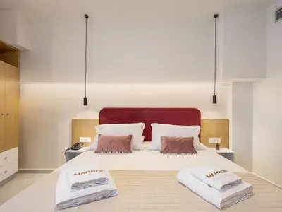 a bedroom with a large white bed with two pillows at Miss Marrone City Hotel in Chania Town