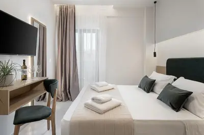 a white bedroom with a desk and a bed at Miss Marrone City Hotel in Chania Town