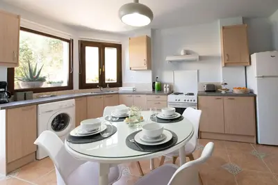 a kitchen with a table with white chairs and a white refrigerator at Natalia's Apartment in Tavronitis in Tavronitis
