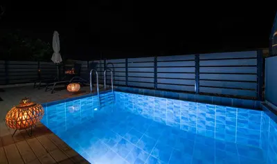 a blue swimming pool at night with a table at 7thHeaven Luxury aprts in Chania Town