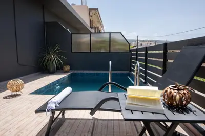 a patio with a table and a swimming pool at 7thHeaven Luxury aprts in Chania Town