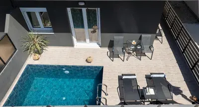 an overhead view of a swimming pool with chairs and a table at 7thHeaven Luxury aprts in Chania Town
