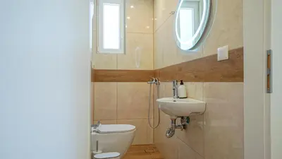 a bathroom with a toilet and a sink and a window at Odyssey Residences 2 in Chania Town