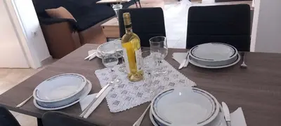 a table with white plates and a bottle of wine at Emmanuel apartment in Agia Marina Nea Kydonias