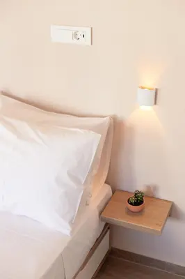 a bed with a white pillow and a wooden table at Serena in Chania Town