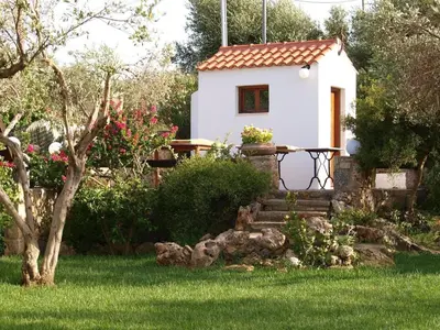 a small white house with a table in a yard at Impressive Platanias Villa Villa Bulma 2 Bedrooms Private Pool in Plataniás