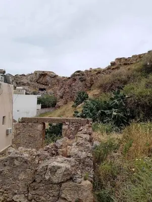 an old stone wall on a hill with a building at Fortezza studio in Palaiochóra