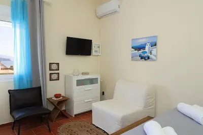 a living room with a bed and a chair at Fortezza studio in Palaiochóra