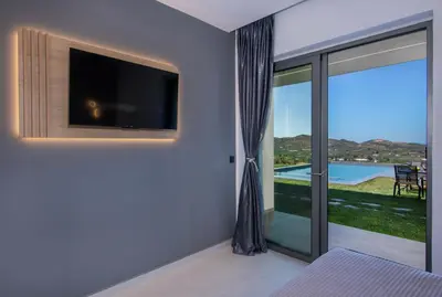 a bedroom with a tv and a sliding glass door at Arithea Villa in Chania Town