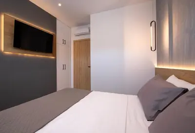 a bedroom with a white bed and a flat screen tv at Arithea Villa in Chania Town