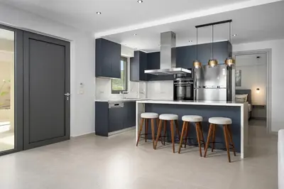 a kitchen with blue cabinets and bar stools at LUXURY VILLA EOS Beachfront 20 metres from the sea in Nopíyia