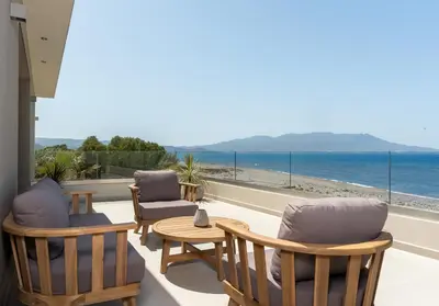 a patio with chairs and a table and the ocean at LUXURY VILLA EOS Beachfront 20 metres from the sea in Nopíyia
