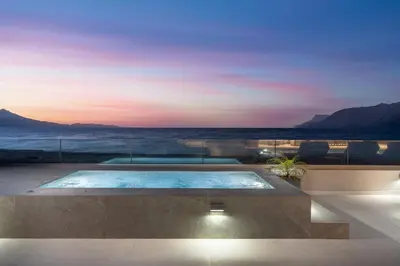 a swimming pool in a house with a sunset at LUXURY VILLA EOS Beachfront 20 metres from the sea in Nopíyia