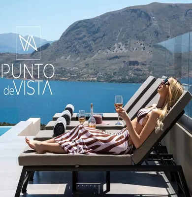 a woman sitting at a table with a glass of wine at Punto De Vista Luxury Villas in Korakiaí