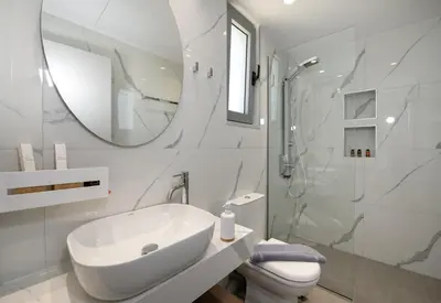 a bathroom with a sink and a toilet and a mirror at Punto De Vista Luxury Villas in Korakiaí