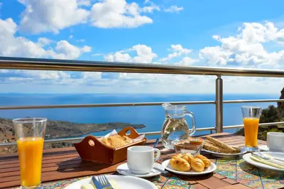 a table with breakfast food and orange juice on a balcony at Livaniana Panoramic View House 1 in Livanianá