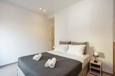 a bedroom with a bed with two pairs of slippers on it at Alex Downtown Holiday Apartment in Chania Town