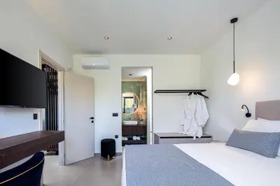 a white bedroom with a bed and a mirror at VillaSaints I Private Pool Villas, Walk to Beach, BBQ in Chania Town