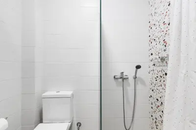 a white bathroom with a shower with a toilet at Central Bliss Apartment in Chania Town