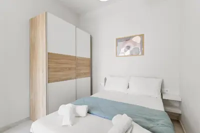 a white bedroom with a bed and a mirror at Central Bliss Apartment in Chania Town