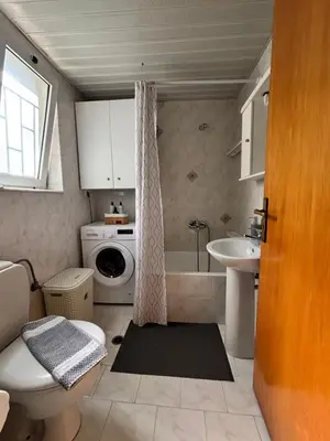 a bathroom with a toilet a sink and a washing machine at Lynne's Harmony Chania Beach Studio in Chania Town
