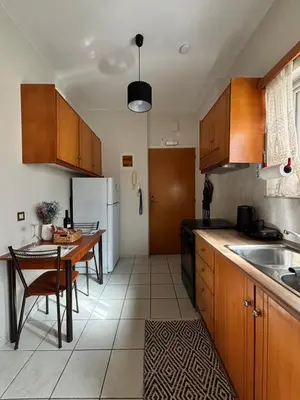 a kitchen with a table and a white refrigerator at Lynne's Harmony Chania Beach Studio in Chania Town