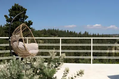 a rattan chair sitting on top of a balcony at Reflection Villa, Heated Pool & Absolute Seclusion, By ThinkVilla in Chania Town