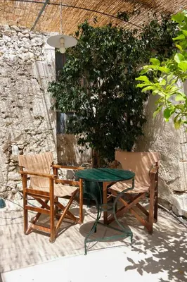 a table and two chairs sitting next to a tree at The Fabrica Falasarna in Plátanos