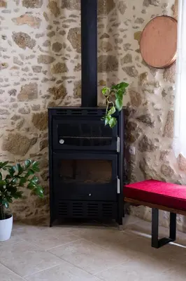 a black stove in a room with a red bench at The Fabrica Falasarna in Plátanos