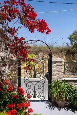 an open gate with red flowers in a garden at The Fabrica Falasarna in Plátanos