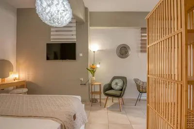 a bedroom with a bed and a chair and a tv at Modern Studio 2 with a Yard in Chania Town