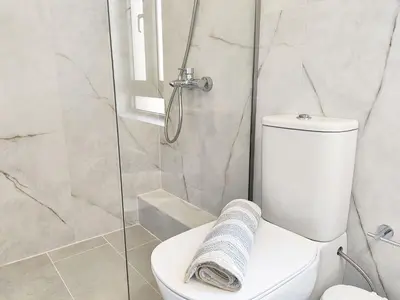 a bathroom with a toilet and a glass shower at Dimitriοs Stone House in Chania Town
