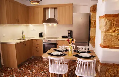 a kitchen with a table with white chairs and a sink at Dimitriοs Stone House in Chania Town