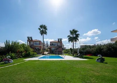 a swimming pool in a yard with palm trees at Socrates Holidays Apt. 2 with Pool near the Beach in Plataniás