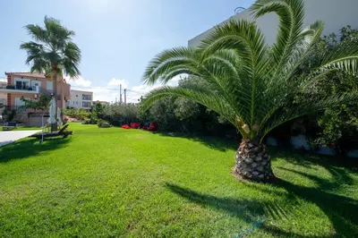 a palm tree sitting on a lawn in a park at Socrates Holidays Apt. 2 with Pool near the Beach in Plataniás