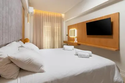 a bedroom with a large white bed with a flat screen tv at CRETA ELENA SUITE in Chania Town