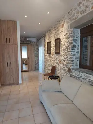 a living room with a couch and a stone wall at Elaion Apartments in Kántanos