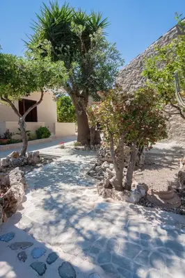 a walkway with trees and rocks in a yard at Liza's Place in Metókhion
