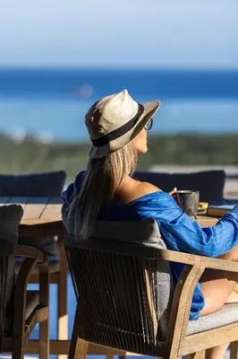 a woman in a hat sitting at a table at Virtus in Mare in Tsivarás