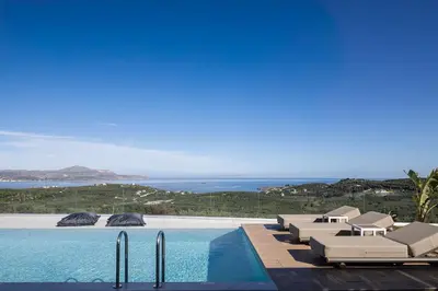a swimming pool with lounge chairs and the ocean at Virtus in Mare in Tsivarás