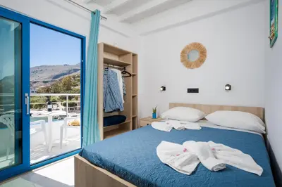 a bedroom with a bed and a balcony at Finikas Resort Sfakia - Seaside Rooms in Loutro