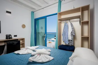 a bedroom with a blue bed with towels on it at Finikas Resort Sfakia - Seaside Rooms in Loutro
