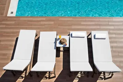 a person sitting at a table next to a pool at Kera Green Villa in Kalyves