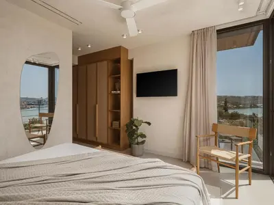 a bedroom with a bed and a tv and a balcony at Villa Albero - Sea View Escape in Souda