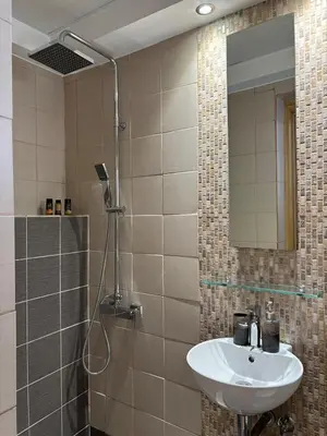 a bathroom with a sink and a shower with a mirror at Duplex apartment city center in Chania Town