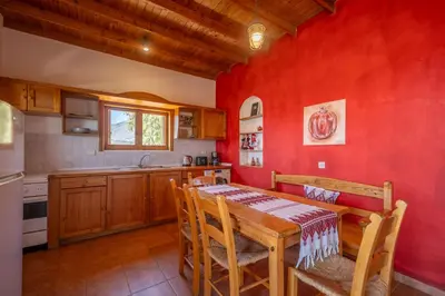 a kitchen with a wooden table and a red wall at BABIS & POPI APARTMENTS in Frangokastello